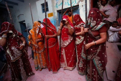 A group of women stand while holding sticks during Lathmar Holi at the village of Barsana